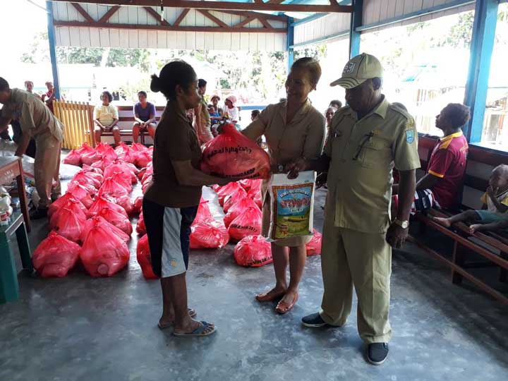 Sekretaris Perindagkop Teluk Wondama, Maria Sri Suliyanti SE, didampingi Kepala Perekda Dekky Torey, menyerahkan paket pasar murah seharga 70 ribu pada salah satu warga Kampung Maimari.